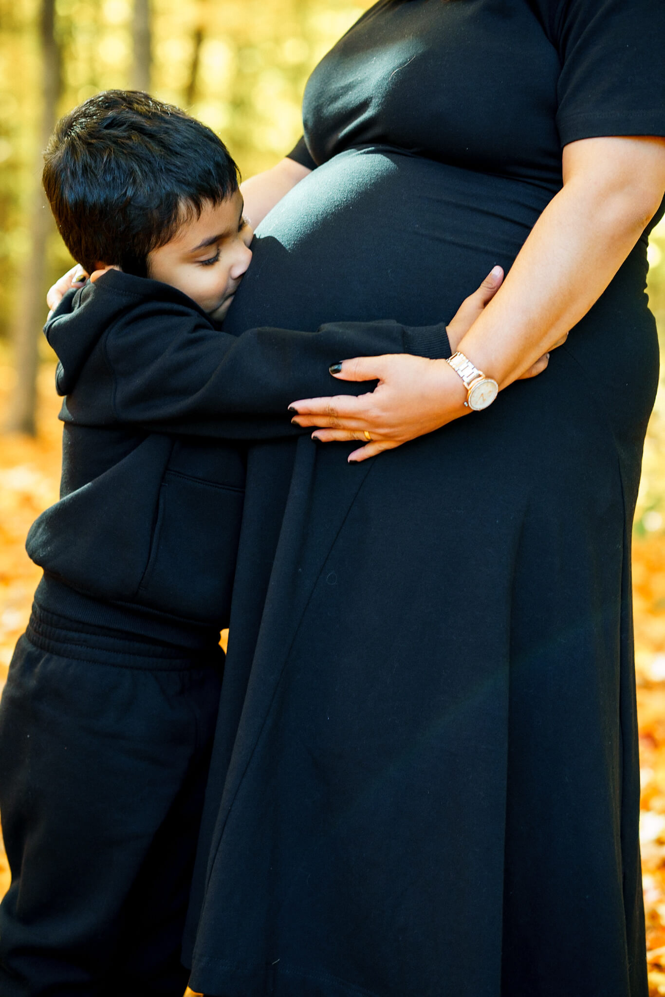 Young boy hugging his mother's pregnant belly during shoot