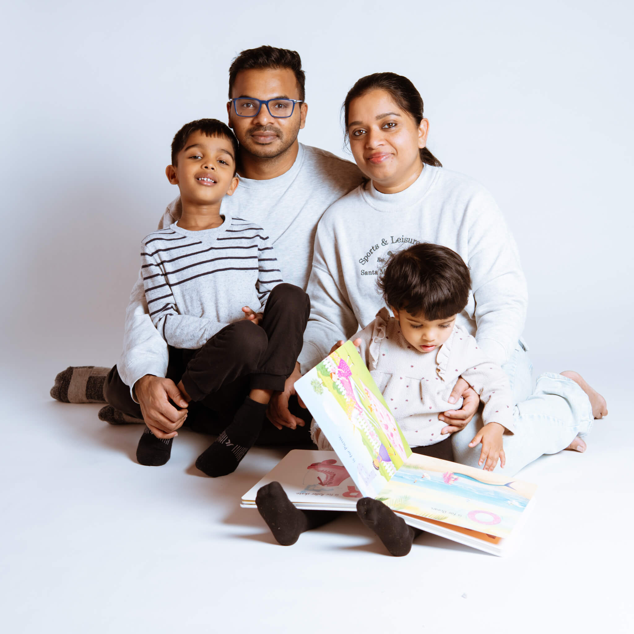A family of four reading a book during a studio session in Kitchener