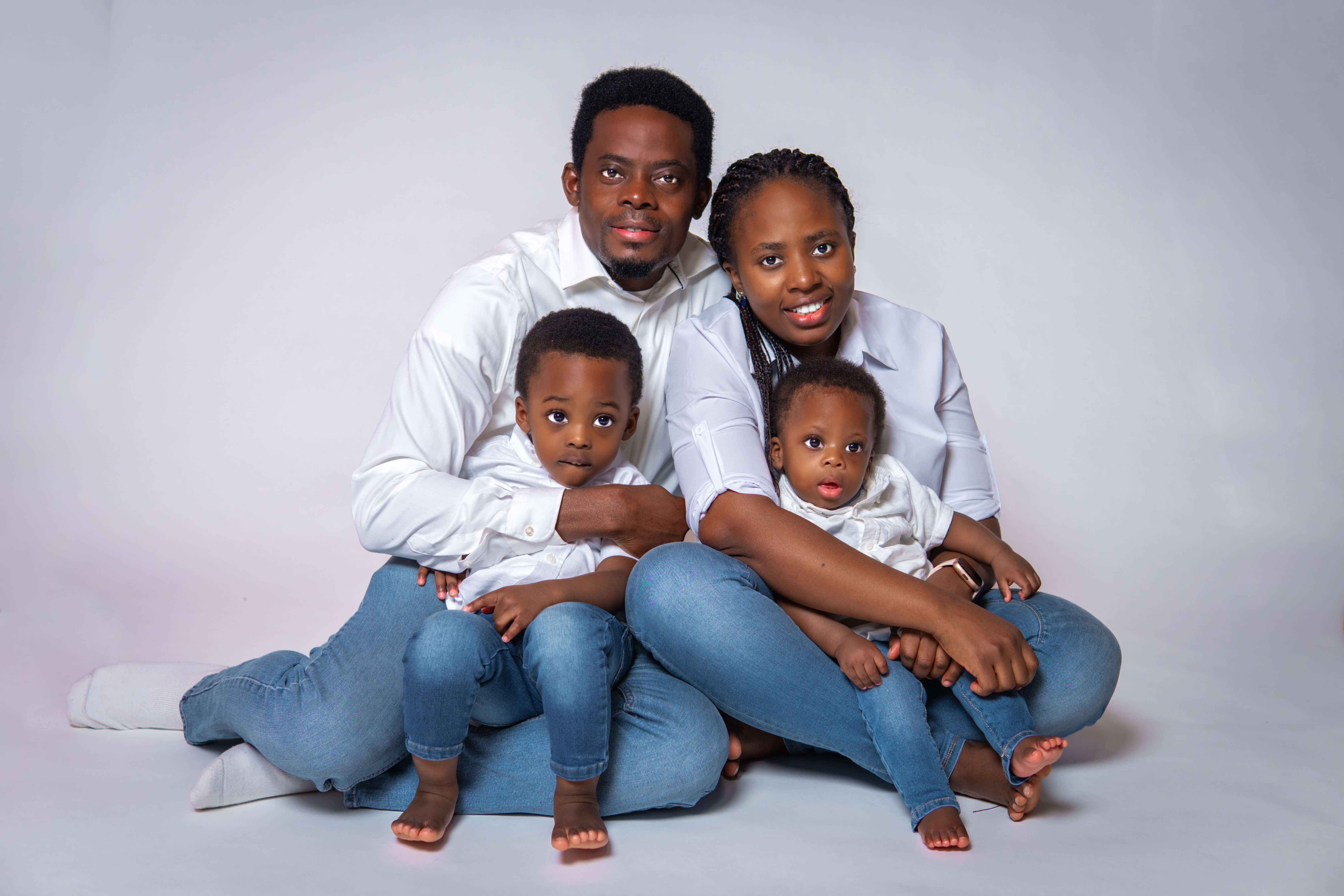 Family of four posing in matching white shirts and denim for a portrait